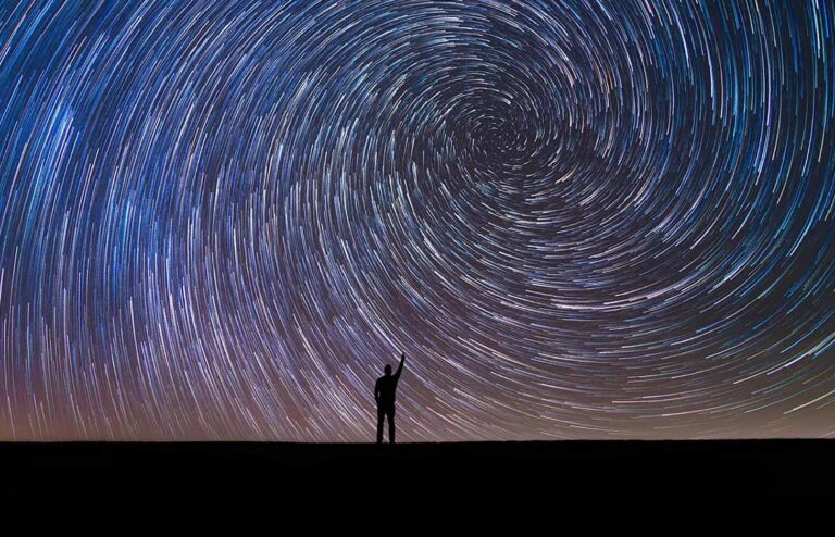 Silhouette of a man pointing at the north star vortex star trail