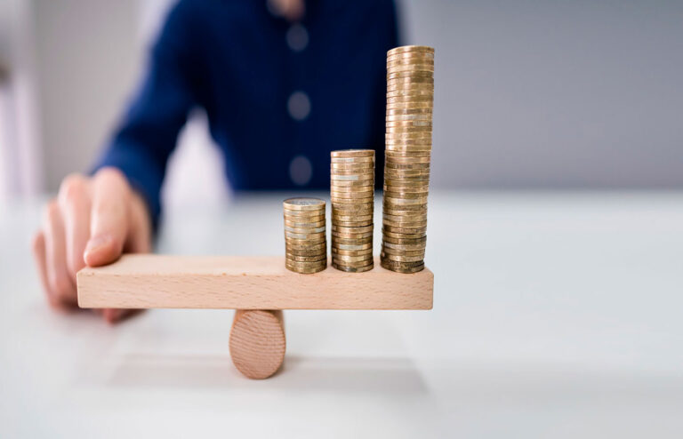 Businessperson Balancing Coins On Wooden Seesaw