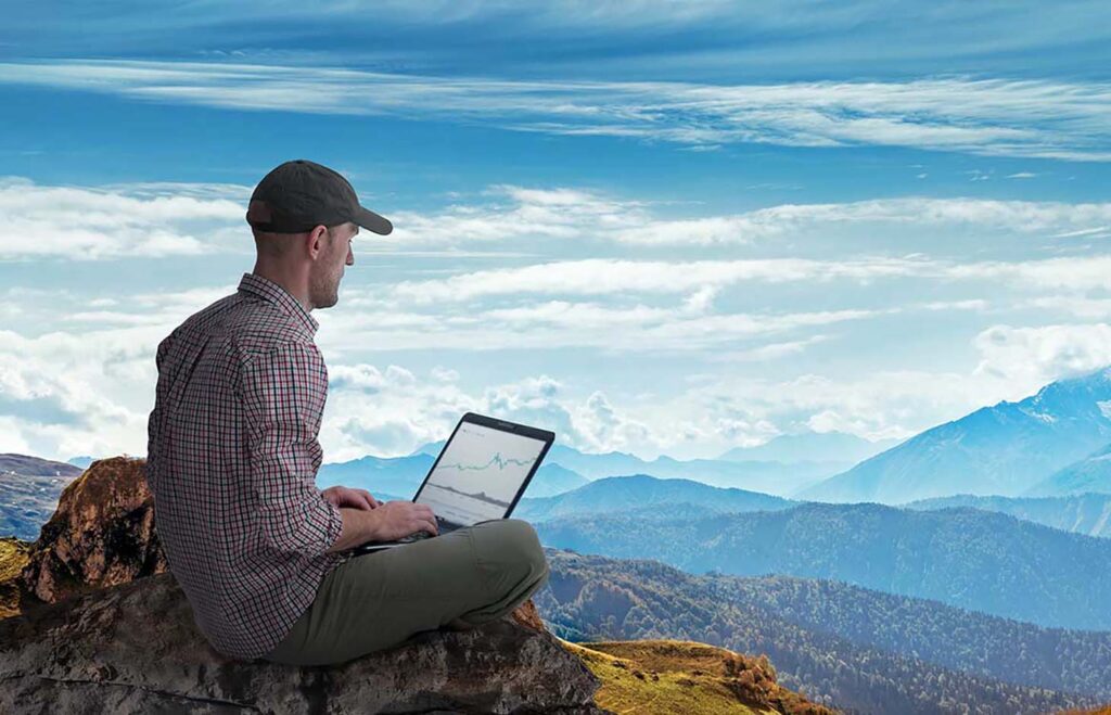 man working remotely outdoors with laptop